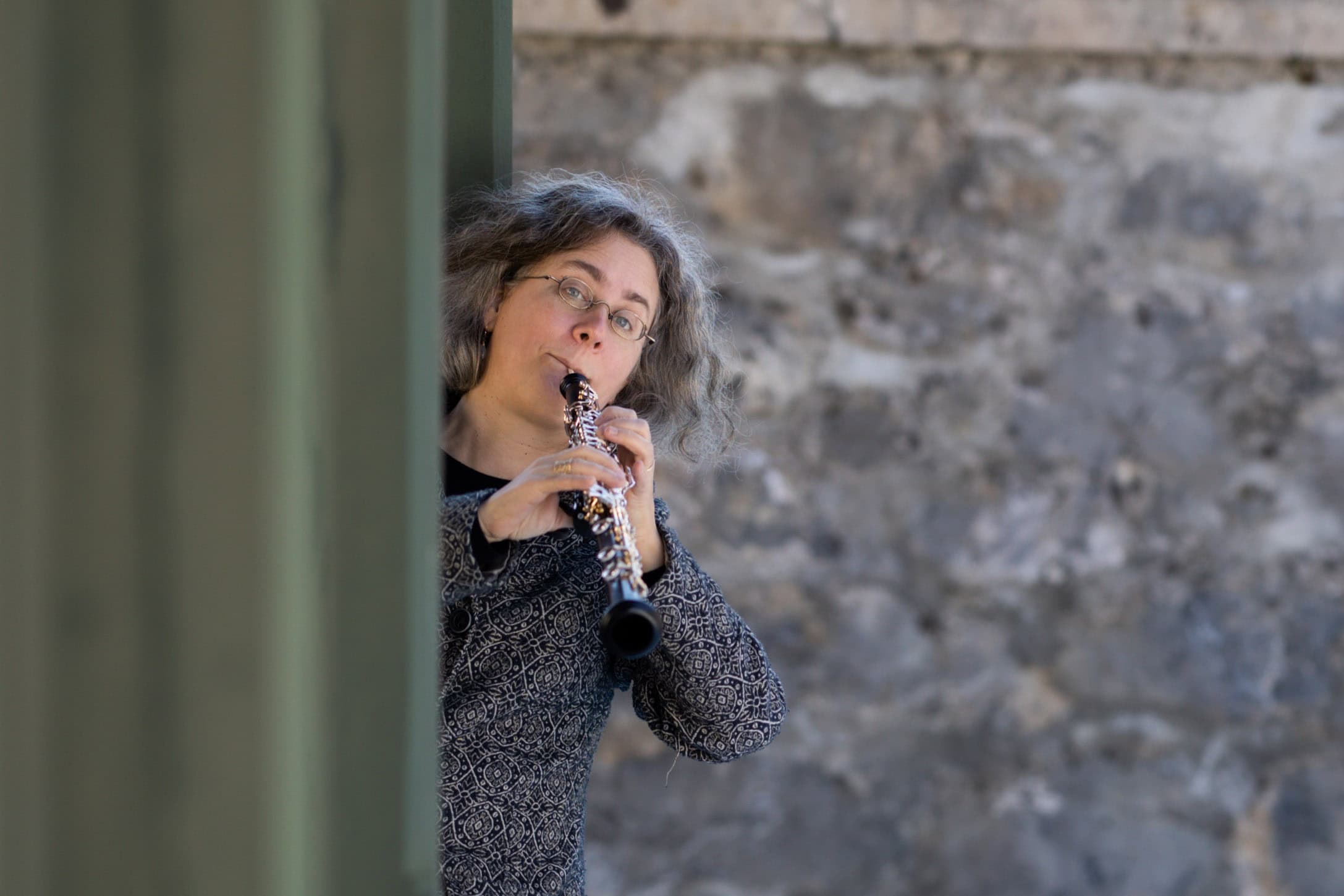 Eine Person mit welligem grauen Haar und Brille spielt Oboe, während sie hinter einer grünen Säule steht; im Hintergrund ist eine verschwommene Steinmauer zu sehen – perfekt für ein Einführungsfoto unter der Rubrik „Über mich“. Eine Person mit welligem grauen Haar und Brille spielt Oboe, während sie hinter einer grünen Säule steht; im Hintergrund ist eine verschwommene Steinmauer zu sehen – perfekt für ein Einführungsfoto unter der Rubrik „Über mich“.